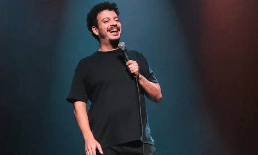 Rodrigo Marques sorrindo com microfone em show de stand-up