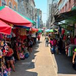 Rua de comércio movimentada com barracas e pessoas, possivelmente no Amazonas.