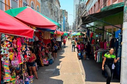 Rua de comércio movimentada com barracas e pessoas, possivelmente no Amazonas.