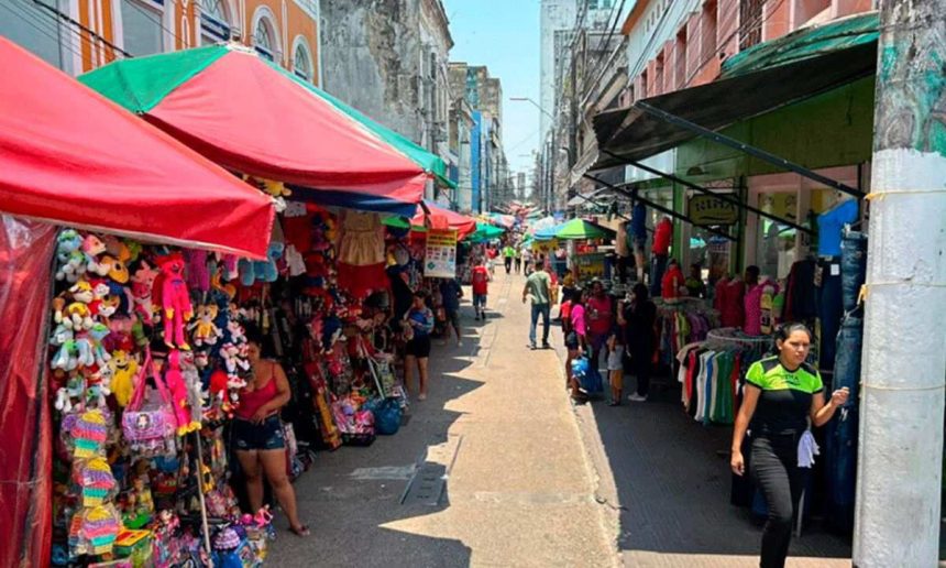 Rua de comércio movimentada com barracas e pessoas, possivelmente no Amazonas.