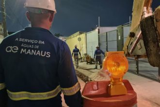 Trabalhadores da Águas de Manaus em obras na Avenida Noel Nutels à noite, com sinalização de segurança.