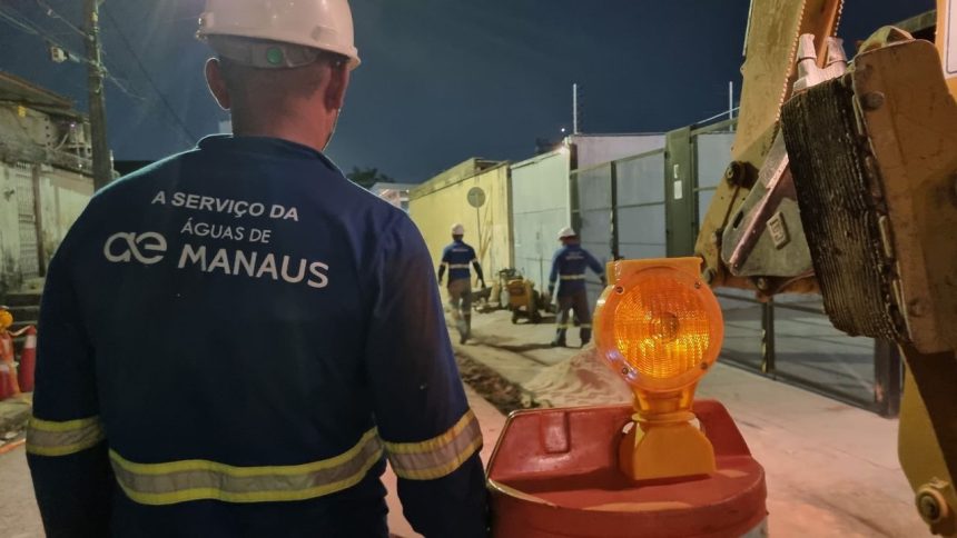Trabalhadores da Águas de Manaus em obras na Avenida Noel Nutels à noite, com sinalização de segurança.