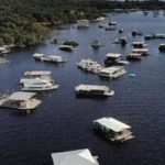 Vista aérea de flutuantes no rio Amazonas, com vegetação ao fundo.