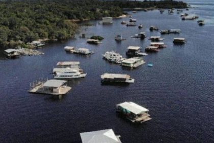Vista aérea de flutuantes no rio Amazonas, com vegetação ao fundo.