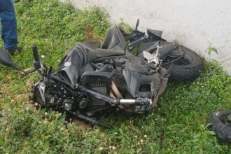 Acidente de moto na Avenida das Torres, com a moto danificada em meio à grama, próximo a um muro.