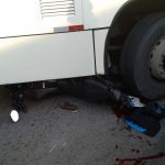 Acidente de trânsito em Manaus: moto esmagada sob ônibus, com sangue no chão.