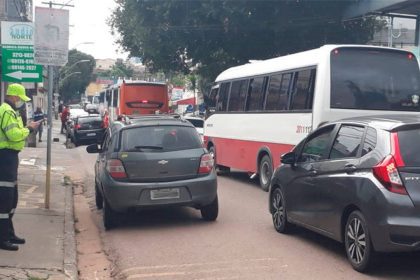 Agente de trânsito fiscalizando veículos em rua de Manaus com tráfego intenso.