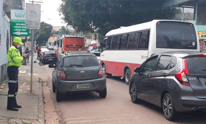 Agente de trânsito fiscalizando veículos em rua de Manaus com tráfego intenso.