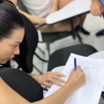 Aluna escrevendo em caderno durante curso de tráfego pago em Manaus.