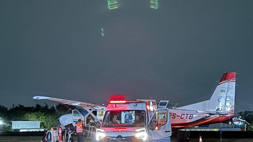 Ambulância e avião Cessna Grand Caravan estacionados em um aeroporto à noite.