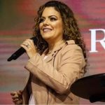 Ana Paula Valadão cantando com microfone em evento gospel.