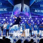 Anúncio do tema do Caprichoso para o Festival de Parintins 2026 com palco azul e figuras.