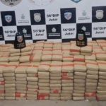 Apreensão de drogas pela polícia, mostrando diversos pacotes empilhados