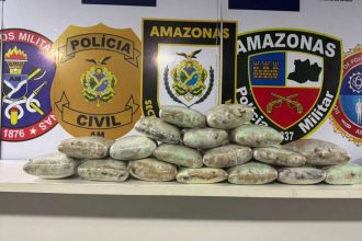Apreensão de drogas pela polícia no Amazonas. Pacotes embalados em cima de uma mesa, com distintivos da polícia no fundo.