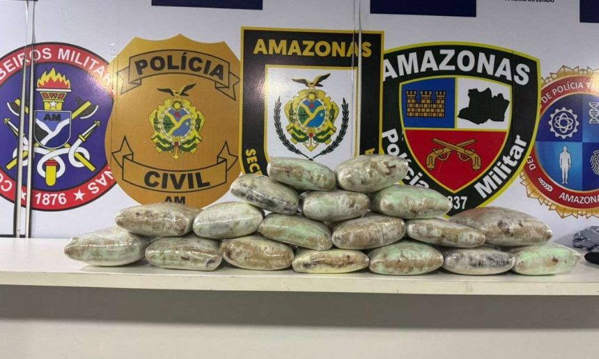 Apreensão de drogas pela polícia no Amazonas. Pacotes embalados em cima de uma mesa, com distintivos da polícia no fundo.