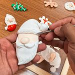 Artesão esculpindo detalhes em um enfeite de Natal de biscuit.