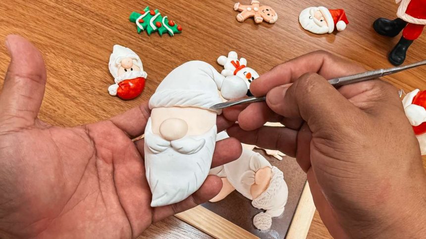 Artesão esculpindo detalhes em um enfeite de Natal de biscuit.