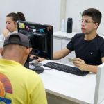 Atendimento em posto de emprego (Sine), com funcionário e cliente interagindo.