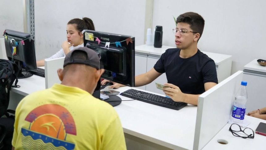 Atendimento em posto de emprego (Sine), com funcionário e cliente interagindo.