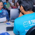 Atendimento no Sine Manaus com pessoas aguardando e documentos sobre a mesa.