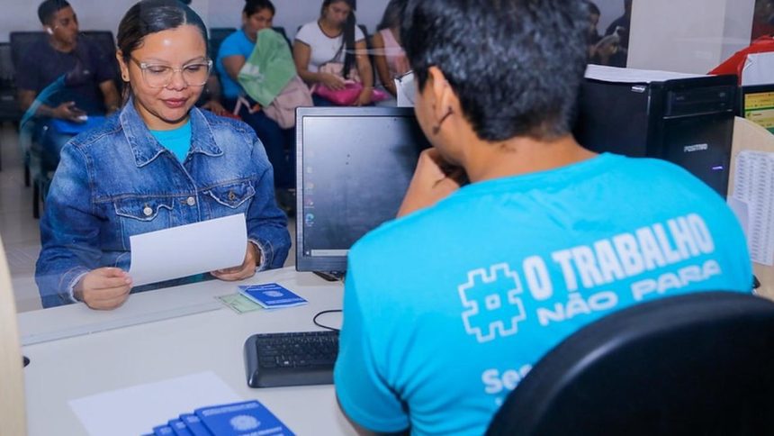 Atendimento no Sine Manaus com pessoas aguardando e documentos sobre a mesa.