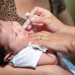 Bebê recebendo vacina oral em campanha de vacinação em UBS.