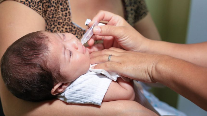 Bebê recebendo vacina oral em campanha de vacinação em UBS.