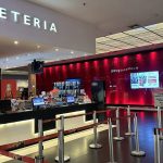 Bilheteria de cinema com letreiro 'BILHETERIA' e fila para atendimento.