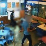 Câmera de segurança registra assalto em cafeteria, com suspeito e vítimas no chão.