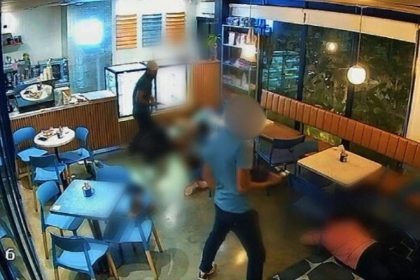 Câmera de segurança registra assalto em cafeteria, com suspeito e vítimas no chão.