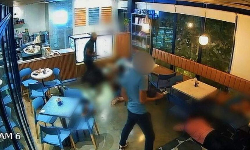 Câmera de segurança registra assalto em cafeteria, com suspeito e vítimas no chão.