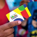 Cartão do programa Bolsa Família sendo segurado por uma pessoa.