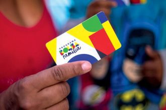 Cartão do programa Bolsa Família sendo segurado por uma pessoa.