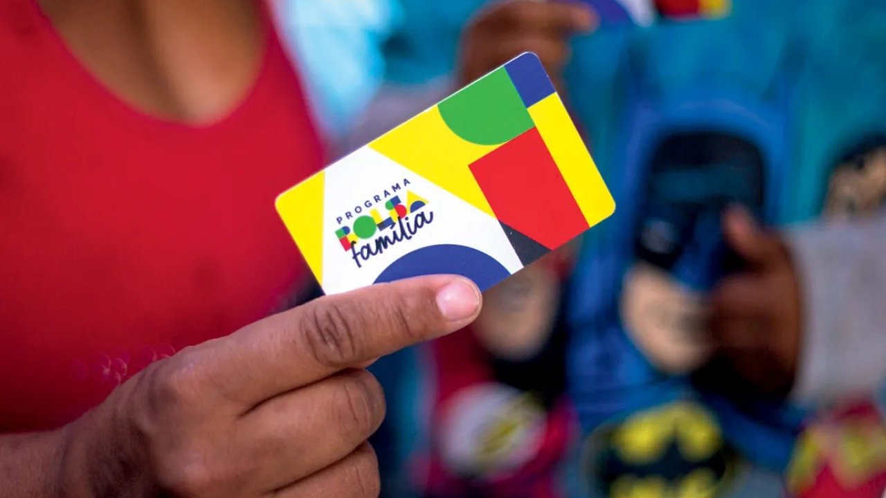 Cartão do programa Bolsa Família sendo segurado por uma pessoa.