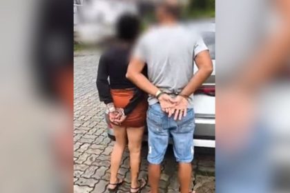 Casal algemado em pé, próximo a um carro, em Manaus.