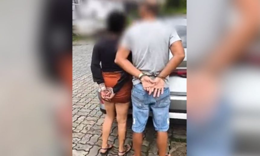 Casal algemado em pé, próximo a um carro, em Manaus.