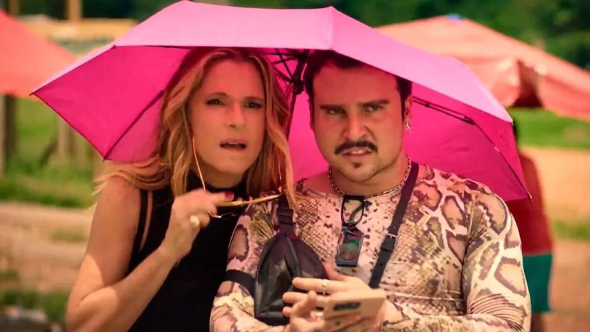 Casal sob guarda-chuva rosa em evento do 'Perrengue Fashion'.