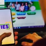 Celular com logo FIES e pessoa usando notebook