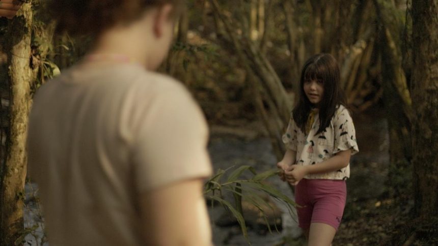 Cena de "A Bota de Lama" com duas crianças em um ambiente natural.