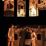 Cena do espetáculo 'O Auto da Compadecida' com atores em palco e cenário.