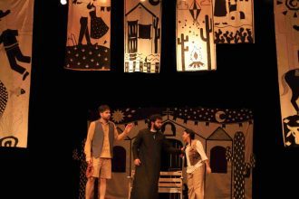 Cena do espetáculo 'O Auto da Compadecida' com atores em palco e cenário.