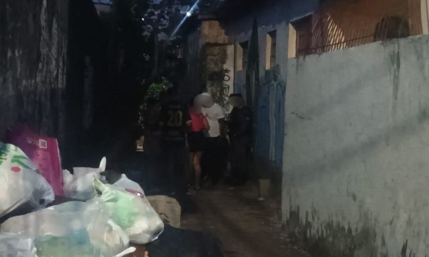 Cena noturna em beco, com pessoas e sacos de lixo.