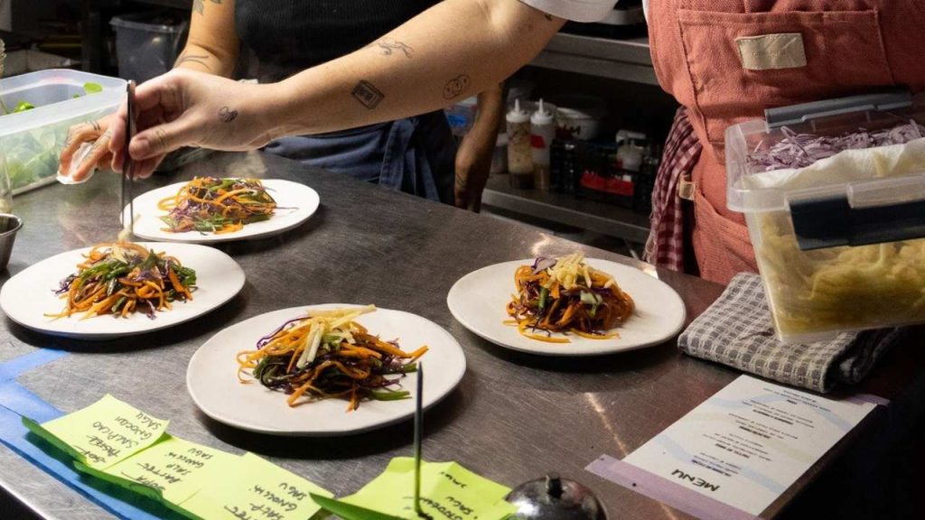 Chef finalizando pratos com ingredientes frescos.