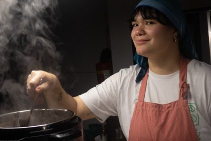Chef paraense sorrindo enquanto cozinha, com vapor subindo de uma panela.