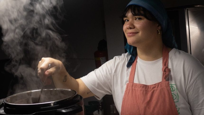 Chef paraense sorrindo enquanto cozinha, com vapor subindo de uma panela.
