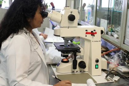 Cientista analisando amostra em microscópio no laboratório.