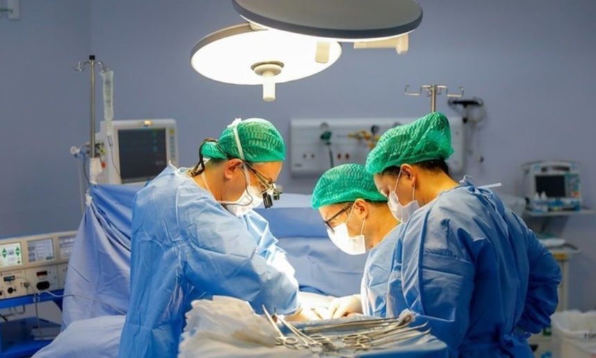 Cirurgiões realizam cirurgia em centro cirúrgico iluminado.