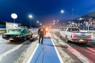 Corrida de arrancada em Iranduba, com carros e público na arquibancada.