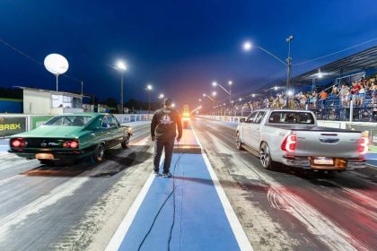 Corrida de arrancada em Iranduba, com carros e público na arquibancada.