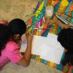 Crianças desenhando juntas em evento literário.